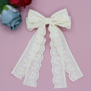 Detail of off-white lace bow hair clip with long ribbons for girls on pink background