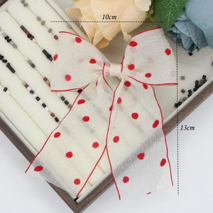 Detail of red polka dot sheer bow hair clip showing 10cm width and 13cm length dimensions