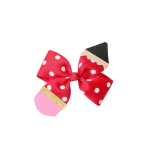 Close-up of a creative pencil bow hair clip with red polka dots and glitter details