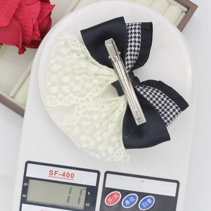 Detail showing a 11g houndstooth ribbon bow hair clip on a white electronic scale