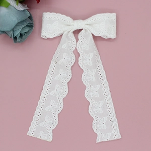 Close-up of white eyelet lace hair bow with long embroidered floral streamers for girls