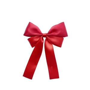 Close-up of a red satin ribbon bow hair clip with elegant long dangling streamers