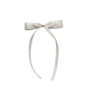 Detail of elegant cream satin bow headband with long flowing ribbons for women