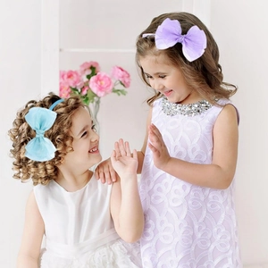 Détail de fillettes portant des bandeaux avec de grands nœuds en tulle bleu et violet