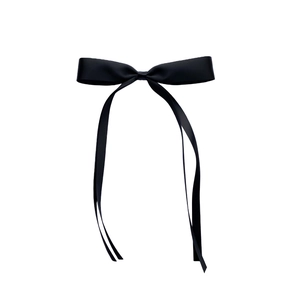 Close-up of a premium black satin bow hair clip with elegant long trailing ribbons