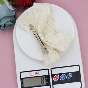 Detailed view of the 8g lightweight cream lace bow hair clip on a digital scale