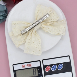 Detailed view of cream lace bow hair clip weighing 8 grams on a digital scale