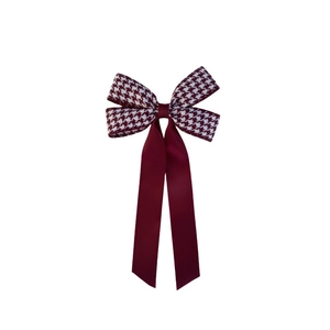 Detail of houndstooth pattern and burgundy satin ribbon on an elegant hair bow clip