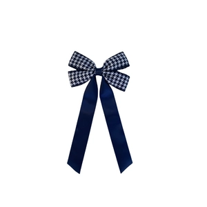 Detailed view of houndstooth fabric and navy blue satin ribbon bow hair clip