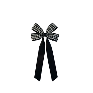 Detail of houndstooth ribbon hair clip with elegant long black flowing fabric streamers