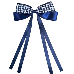 Detail of navy blue satin ribbons and houndstooth bowknot hairpin with long streamers