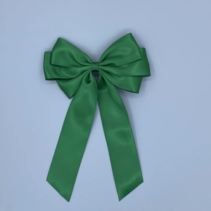 Detail view of smooth green satin bow hairclip with long ribbon tails and elegant silk texture