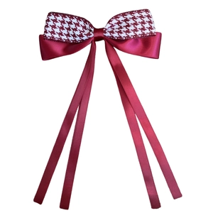 Detail of red and white houndstooth bow hair clip with long satin ribbon streamers