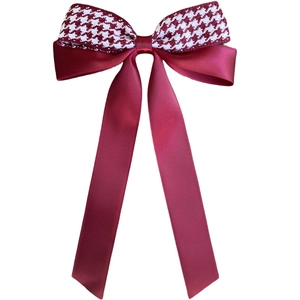 Detail of red satin and houndstooth bow hair clip with long elegant ribbons