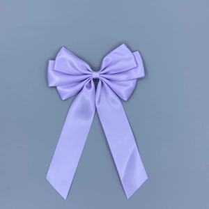 Close-up of lavender satin bow hair clip with elegant long ribbons and silky texture