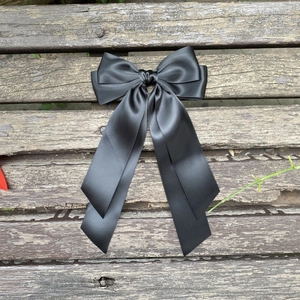 Vue détaillée d'un nœud papillon en satin noir avec de longs rubans sur un fond en bois