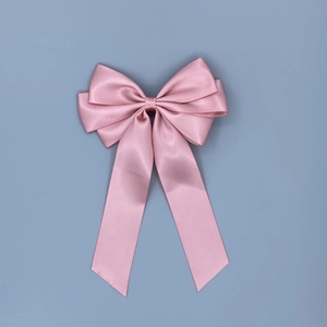 Close-up of pink satin double-layer bow hair clip with long ribbons on blue background