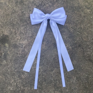 Détail d'un nœud en satin blanc avec rubans fluides sur un fond en pierre texturée