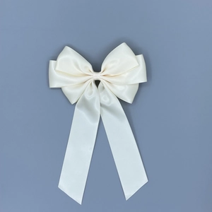Detail of a creamy white satin ribbon bow hair clip with elegant long streamers