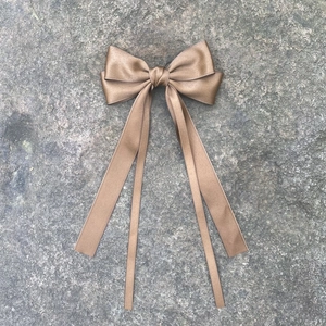 Détail d'une pince à cheveux avec long ruban en satin bronze doré sur pierre naturelle