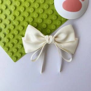 Elegant cream satin bow hair clip with long ribbons and smooth silk texture