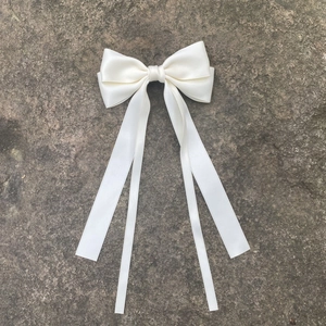 Détail de la pince à cheveux nœud en satin ivoire avec d'élégants rubans longs