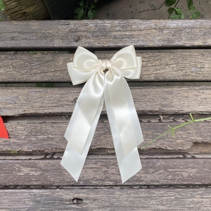 Détail d'un nœud papillon en satin crème avec longs rubans sur surface en bois