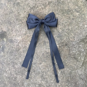 Détail d'un nœud papillon en satin bleu marine avec de longs rubans fluides sur pierre