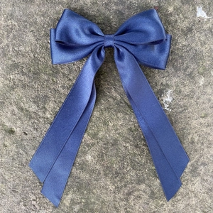 Dettaglio del fermaglio per capelli in raso blu navy con doppio fiocco e nastri
