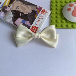 Dettaglio di un'elegante clip per capelli in raso bianco crema con texture lucida in seta