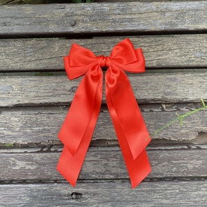 Détail d'un grand nœud en satin rouge à plusieurs couches avec de longs rubans soyeux