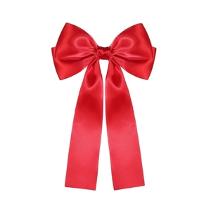 Detailed view of large red satin bow hair clip with long flowing ribbons and glossy texture