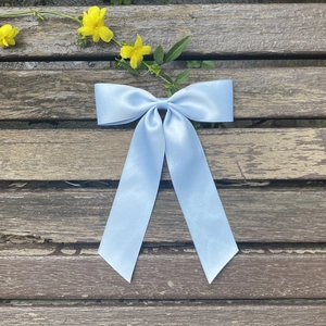 Macro detail of the light blue satin bow hair clip with elegant long hanging ribbons