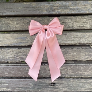 Gros plan détaillé d'un nœud en satin rose avec d'élégants rubans longs et fluides