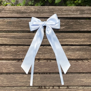 Detail of light blue satin hair bow with long ribbons on a dark wood background
