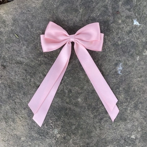 Fiocco per capelli in raso rosa con lunghi nastri su superficie in pietra grigia