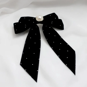 Detail of black velvet bow hair clip with central square pearl and sparkling rhinestones