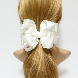 White ribbed fabric layered bow hair clip for girls shown on model with light gray background