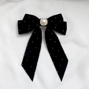 Detailed view of black velvet bow hair clip with square pearl and sparkling rhinestones