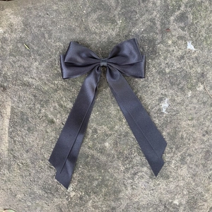 Fermaglio per capelli con fiocco in raso nero e nastri lunghi su fondo in pietra