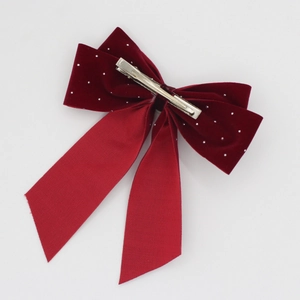Detail of red velvet hair bow clip with pearls and long satin streamers on white base