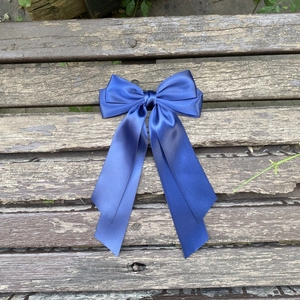 Détail d'un élégant nœud à cheveux en satin bleu foncé avec de longs rubans sur bois