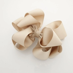 Detailed macro view of the layered beige grosgrain ribbon texture on the bow hair clip