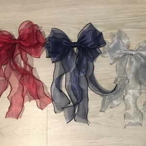 Close-up of three layered organza bow hair clips with long wavy ribbons in various colors