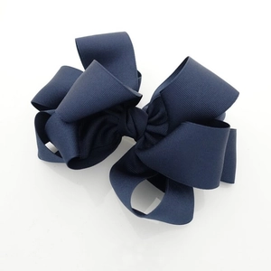 Detailed close-up showing the layered grosgrain ribbon texture of a navy blue bow hair clip