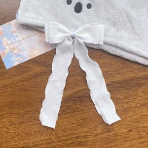 Detail of white pleated chiffon ribbon bow on a gray plush koala headband accessory