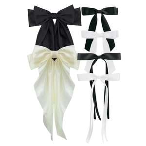 Detail of satin bow hair clips in black and cream white with elegant long ribbons