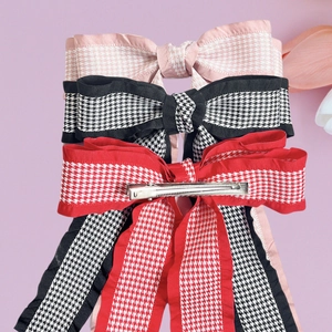 Three houndstooth bow hair clips with long ribbons in pink, black, and red colors