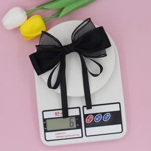 Elegant multi-layer black mesh and velvet bow hair clip with ribbons on pink background