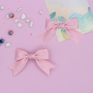 Detailed view of pink satin ribbon bow hair clips with soft silk texture and center knot